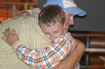 Tristin Pelloni hugs his uncle Todd Morris after winning grand champion market swine in his first year of showing.