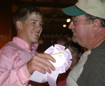Trey Morris receives congratulations from his grandfather Gerald Morris after winning reserve champion market swine at the Rio Blanco County Fair.