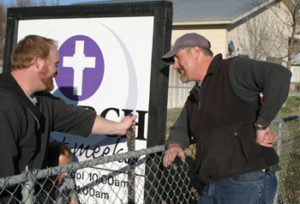  John Brown, left, Bob Lange, right, and Burnie Cox, kneeling, helped take down the sign for The Church at Meeker on Sunday as part of the church’s move to a new meeting place on the west side of town. 