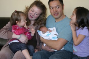 Amy Que, holding her daughter Evangeline, has had two home births during the time the Ques have lived in Meeker. Husband Michael holds Samuel, who was born the day after Christmas. Oldest daughter Charlotte, far right, was born in a hospital in Nebraska, where home births are illegal using a midwife.