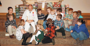 Pastor Jon at United Methodist Church in Meeker sits with some of the children who helped fill 169 local Samaritan’s Purse gift-filled shoeboxes that will be distributed around the world as part of a project to bring Christmas presents to children who have never received a gift.