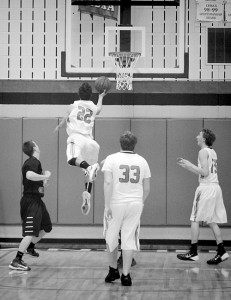 Senior Andrew Morton (22) drives to the basket as junior Layne Mecham (33) and junior Mitchell Webber (15) look on.