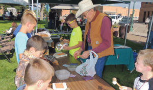 Colorado saddle maker Bob Klenda spent much of Saturday’s “50 Years Wild” celebration in downtown Meeker working with children and showing how he works. He is seen here helping the kids learn to stamp patterns onto leather.