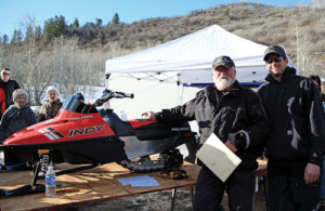 Mike Sizemore, left, presents the grand prize of a Polaris 120 child’s snowmobile  from the “I Ride With James” snowmobile and poker run on Sunday to Luke Weeldreyer of Craig. First place and $1,000 went to Cole Steiner, second place and $500 went to Chris King, and third place and $250 went to Deb Overton. More than 100 riders took part in the ride and poker run despite a lack of snow at the base camp at  Lost Creek Trailhead. The event is in memory of Mike and Kathy Sizemore’s son, James, who was killed Feb. 20, 2011, in an avalanche on nearby Sand Peak.