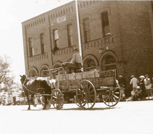 Horse-drawn wagon passes in front of the IOOF building.