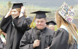 Marcus Archuleta, center, one of the graduating members of the Meeker Class of 2015, is assisted by Reagan Pearce, left, and Brittany Smith, right, as he gets ready to tell the class to turn their tassels, a symbol that the members of the senior class were finally considered to have officially graduated. 