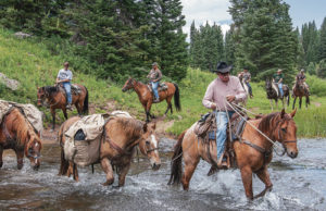Bruce Clatterbaugh of Adams Lodge Outfitters leads a group of veterans on a trail ride across a stream in the Flat Tops northwest of Meeker near Marvine Lake.