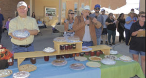  J.H. Sheridan holds the pie being auctioned by Bryce Purkey as part of an auction to benefit 4-H. The festival is co-sponsored by White River Electric Association and the ERBM Recreation and Parks District.