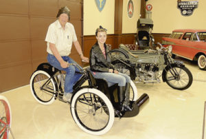 Bud Striegel, owner of the newly opened Rangely Automotive Museum, put employee Kelsey Peters in the passenger seat of this 1907 Indian Tri-car Sunday, one of the many motorcycles and automobiles on display at the museum. The museum will hold its grand opening May 28. The museum is open on Thursdays, Fridays, Saturdays and Sundays at the intersection of Stanolind and Highway 64. 