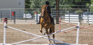 Clearing the hurdle, Deanna Woods of Meeker is seen here competing in the junior English equitation class on Saturday at the Rio Blanco County Fair in Meeker. The horse show took up the fair action on  Friday and Saturday but the livestock and exhibits of all sorts will keep fairgoers busy starting today and concluding with the livestock auction on Saturday evening.